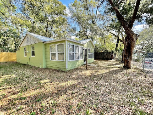 view of side of property featuring fence and metal roof