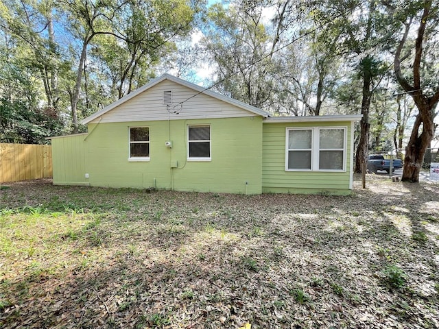 view of side of property featuring concrete block siding and fence