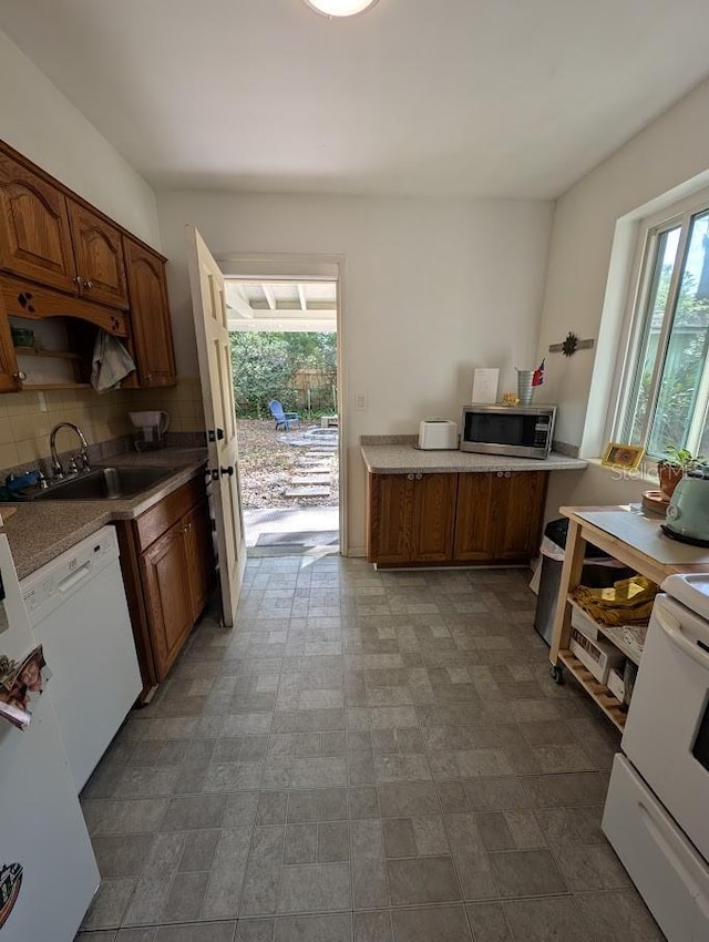 kitchen with a sink, dishwasher, stainless steel microwave, range, and backsplash