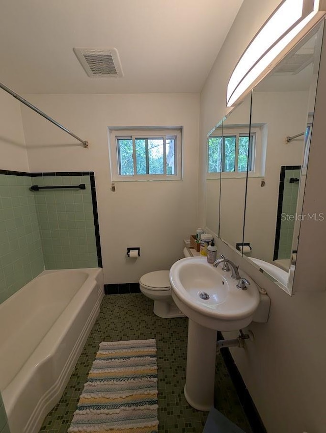 bathroom with shower / bathing tub combination, toilet, visible vents, and a sink