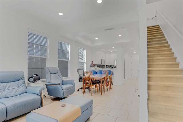 living area with recessed lighting, a raised ceiling, stairs, and light tile patterned floors