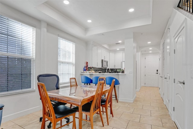 dining room with a tray ceiling, light tile patterned flooring, recessed lighting, and baseboards