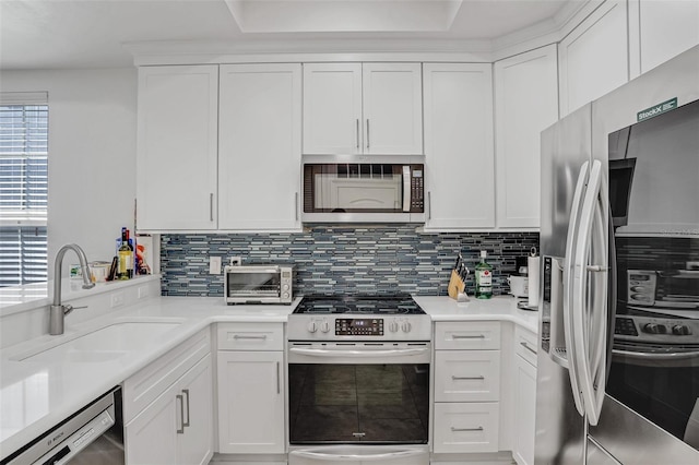 kitchen featuring a sink, backsplash, appliances with stainless steel finishes, and white cabinets