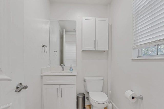 half bathroom featuring toilet, vanity, and baseboards