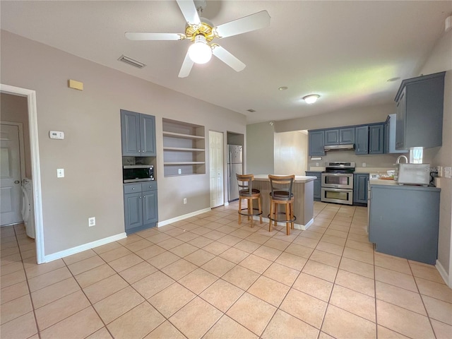 kitchen featuring a kitchen bar, a kitchen island, stainless steel appliances, light tile patterned flooring, and ceiling fan