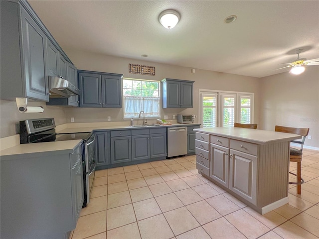 kitchen with a sink, light countertops, under cabinet range hood, and stainless steel appliances