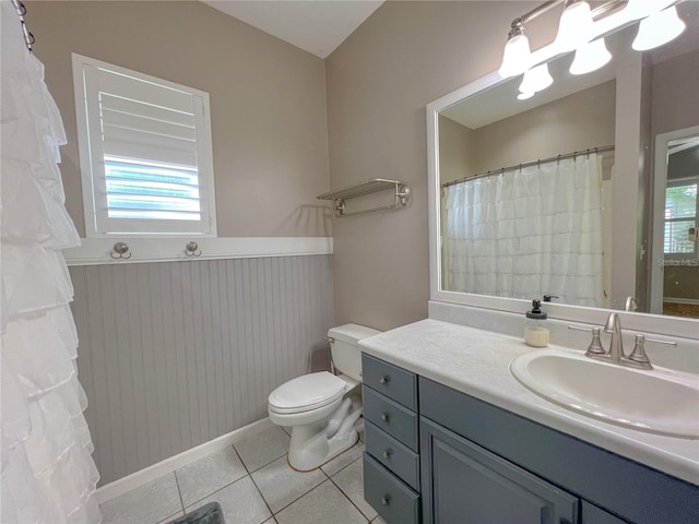 bathroom with tile patterned floors, toilet, a healthy amount of sunlight, and vanity