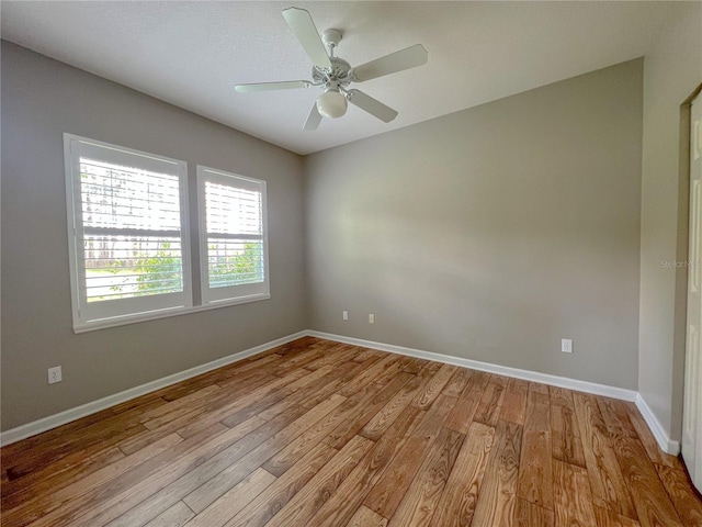 spare room featuring a ceiling fan, baseboards, and light wood finished floors