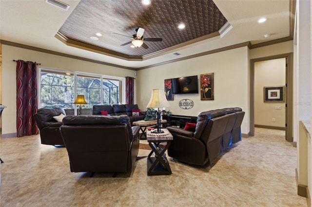 living room with a ceiling fan, baseboards, visible vents, a tray ceiling, and ornamental molding