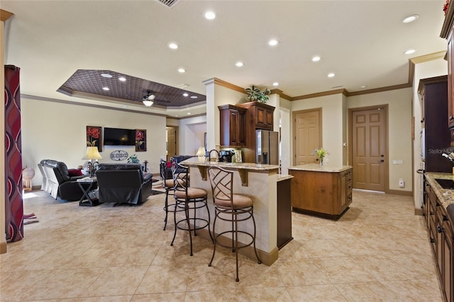 kitchen with a kitchen island, stainless steel fridge with ice dispenser, open floor plan, a kitchen breakfast bar, and a peninsula