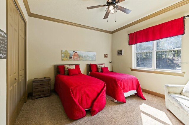 carpeted bedroom featuring a closet, ceiling fan, crown molding, and baseboards
