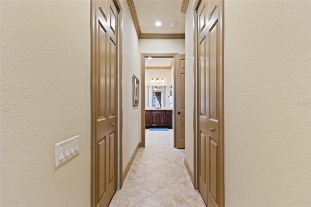 hall with light tile patterned floors, baseboards, crown molding, and a textured wall