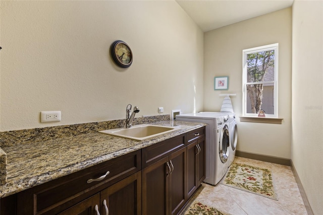 washroom featuring baseboards, washer and clothes dryer, light tile patterned floors, cabinet space, and a sink