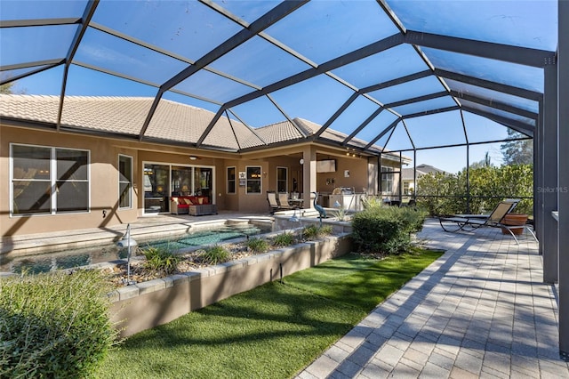 rear view of house with stucco siding, glass enclosure, and a patio area
