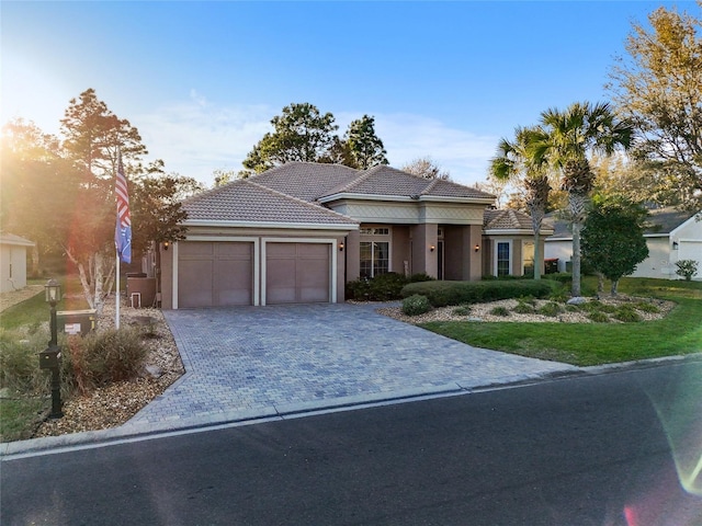 view of front of property with stucco siding, a tile roof, decorative driveway, and a garage