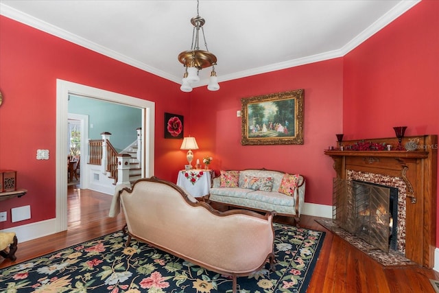 living room with crown molding, baseboards, stairway, a fireplace, and wood finished floors