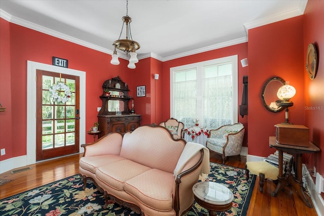 living area with visible vents, crown molding, baseboards, and wood finished floors