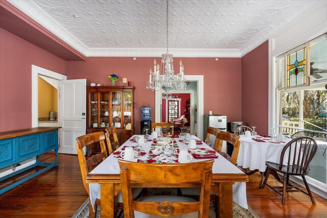 dining room with a notable chandelier, ornamental molding, an ornate ceiling, and wood-type flooring
