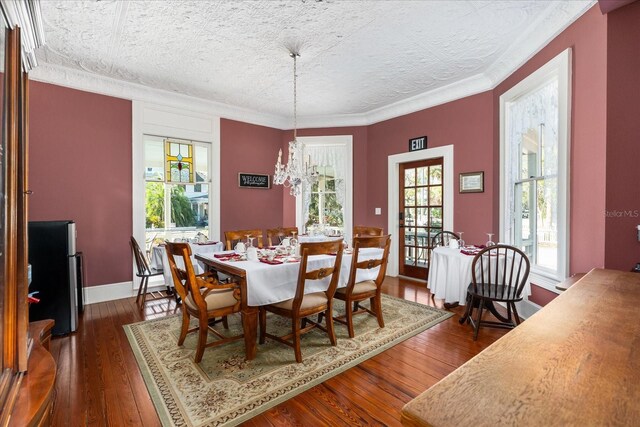 dining room with a textured ceiling, dark wood-style floors, crown molding, baseboards, and a chandelier