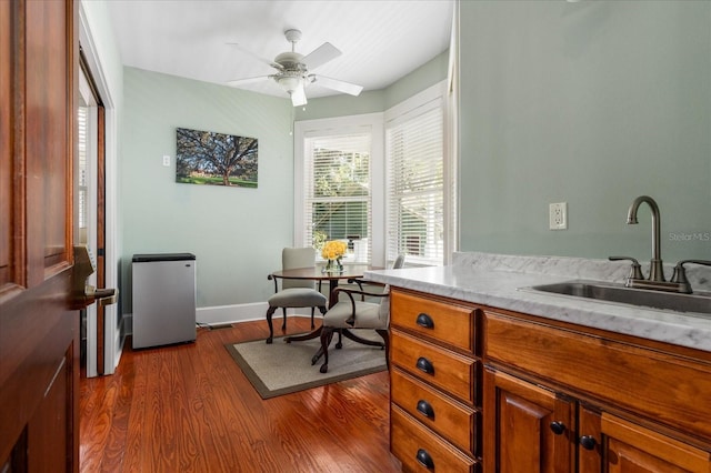 home office featuring dark wood finished floors, baseboards, a ceiling fan, and a sink