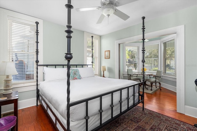 bedroom featuring baseboards, multiple windows, and wood finished floors