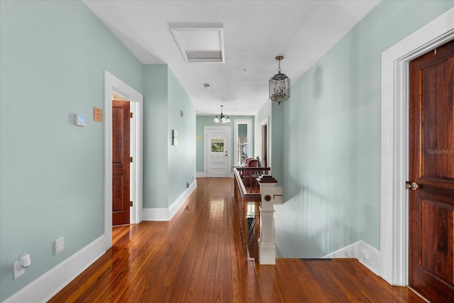 hall with baseboards, an upstairs landing, an inviting chandelier, and hardwood / wood-style floors