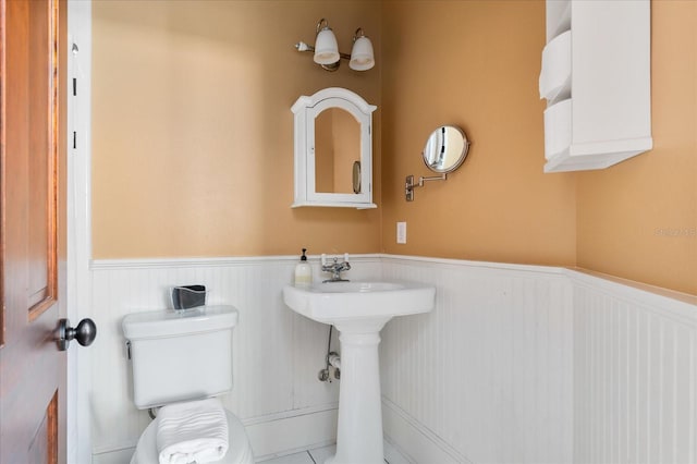 bathroom with a sink, a wainscoted wall, and toilet