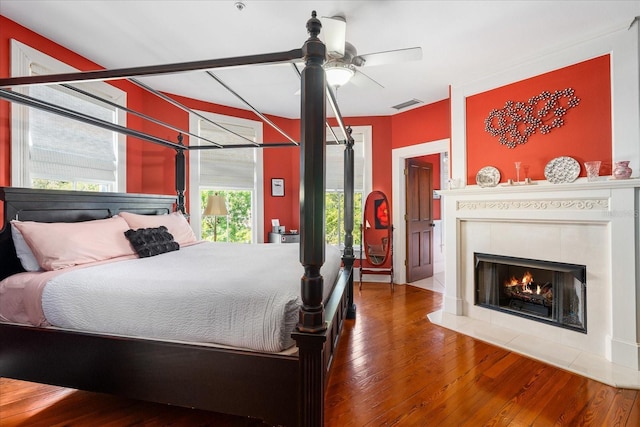 bedroom featuring visible vents, a tile fireplace, and hardwood / wood-style floors