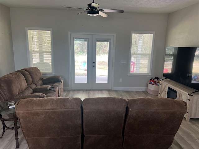 living room with light wood-type flooring, a ceiling fan, baseboards, and french doors