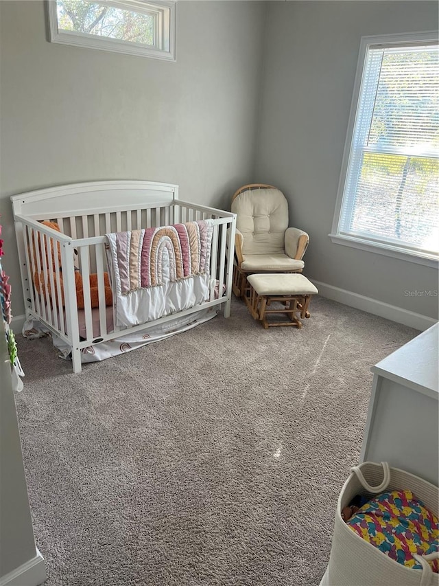 carpeted bedroom featuring baseboards and a nursery area