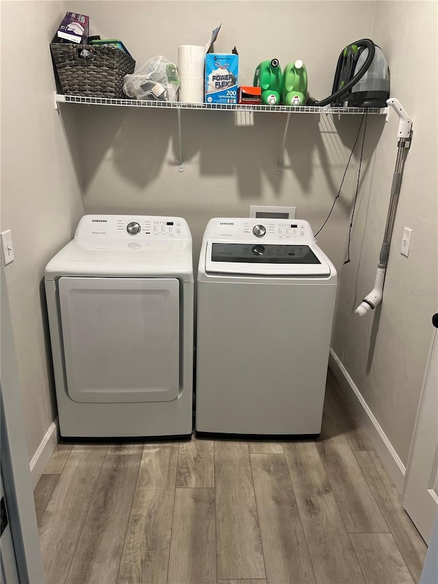 laundry area with baseboards, wood finished floors, independent washer and dryer, and laundry area