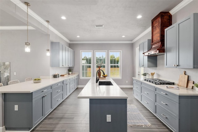 kitchen with stainless steel gas stovetop, a sink, gray cabinets, and crown molding