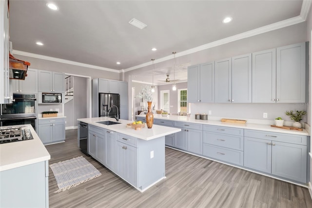 kitchen featuring light countertops, a sink, stainless steel appliances, and ornamental molding