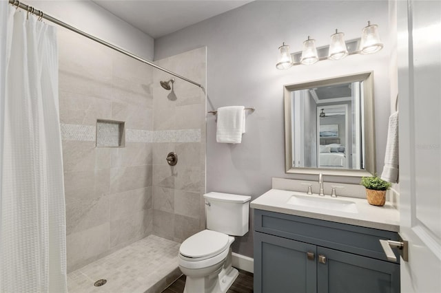full bathroom featuring toilet, vanity, baseboards, and tiled shower