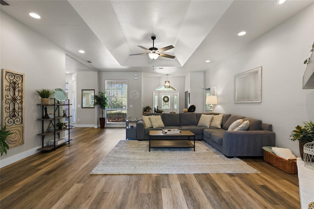 living area featuring a raised ceiling, a ceiling fan, wood finished floors, baseboards, and recessed lighting