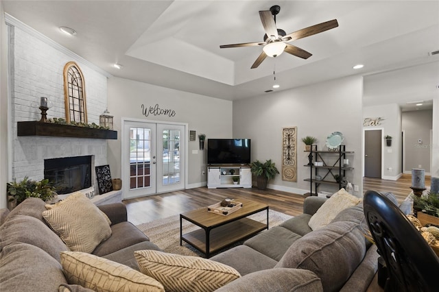 living room with a tray ceiling, baseboards, ceiling fan, and wood finished floors
