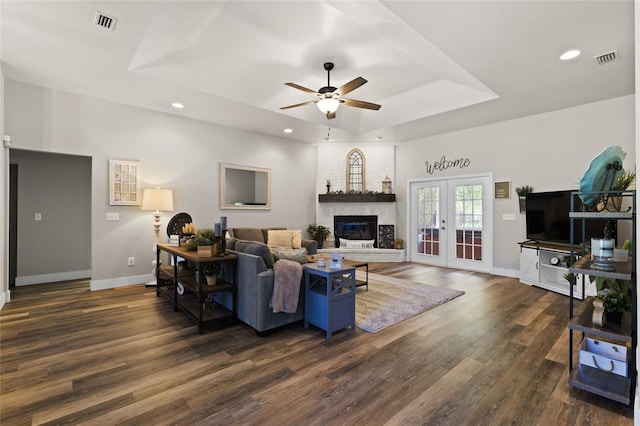 living room featuring dark wood-style flooring, visible vents, a ceiling fan, a raised ceiling, and french doors