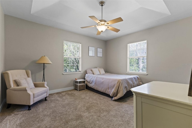 bedroom featuring a ceiling fan, light carpet, baseboards, and multiple windows