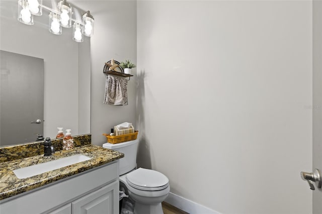 bathroom with baseboards, toilet, and vanity