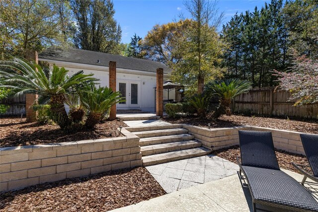 view of front of house with fence, french doors, and a patio
