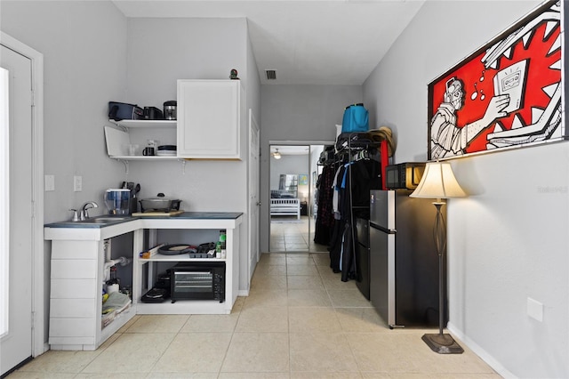 kitchen featuring open shelves, freestanding refrigerator, light tile patterned floors, visible vents, and white cabinets