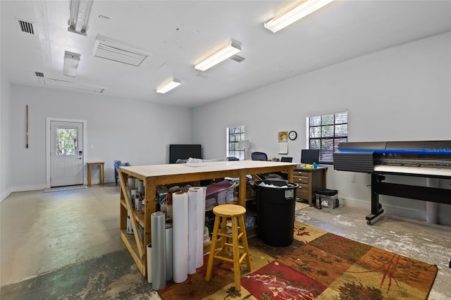 office space with unfinished concrete floors, a wealth of natural light, baseboards, and visible vents