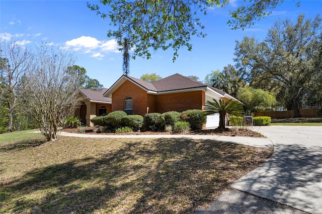 view of front of home featuring concrete driveway, an attached garage, fence, brick siding, and a front lawn
