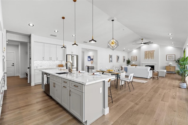 kitchen with a ceiling fan, a sink, open floor plan, appliances with stainless steel finishes, and visible vents