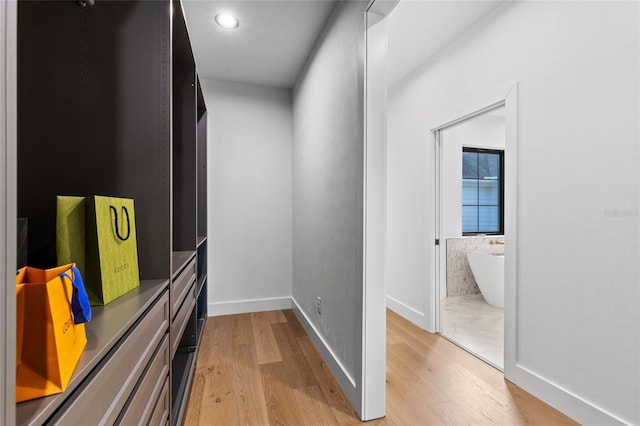 hallway with baseboards, recessed lighting, and light wood-style floors