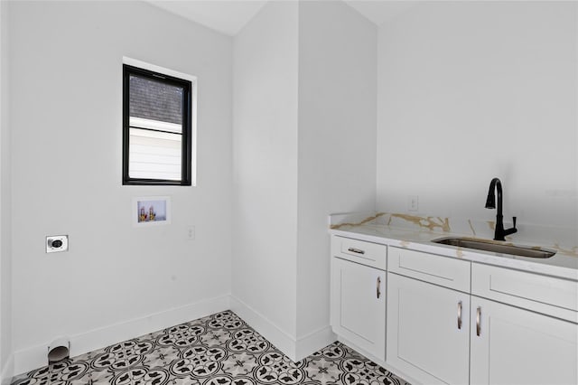 clothes washing area with a sink, hookup for a washing machine, baseboards, electric dryer hookup, and cabinet space