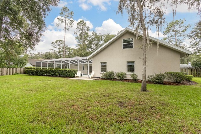5620 NW 45th Ln, Gainesville, FL 32606 - rear view of house featuring stucco siding, fence private yard, glass enclosure, and a patio