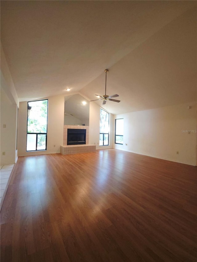 7717 SW 22nd Ave, Gainesville, FL 32607 - unfurnished living room with wood finished floors, plenty of natural light, lofted ceiling, a fireplace, and a ceiling fan