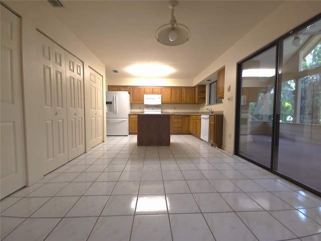 7717 SW 22nd Ave, Gainesville, FL 32607 - kitchen with white appliances, brown cabinetry, a center island, light tile patterned floors, and a sink