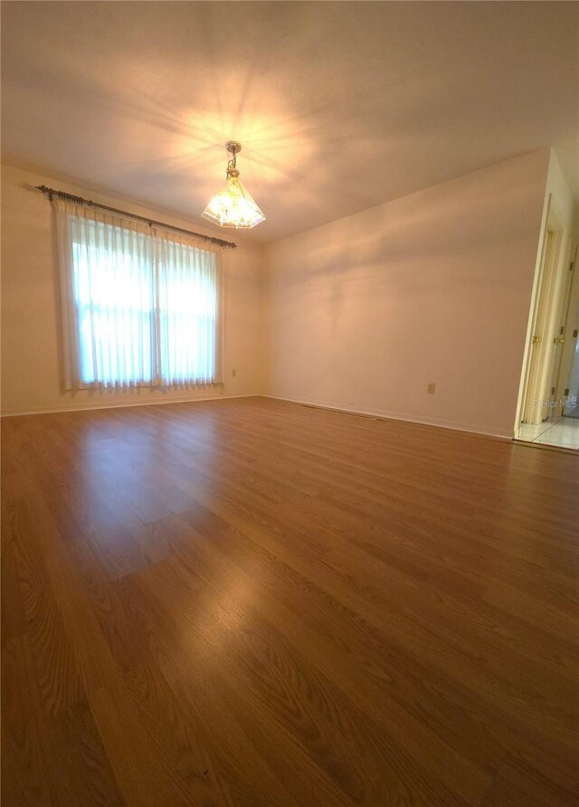 7717 SW 22nd Ave, Gainesville, FL 32607 - empty room featuring a chandelier, wood finished floors, and baseboards